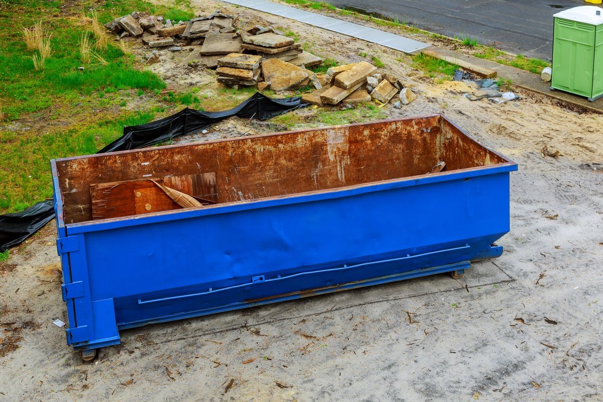 Blue construction debris container filled with garbage bin